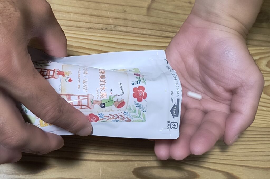 健康美的水素Premiumの袋と、手のひらに乗せたカプセル1粒