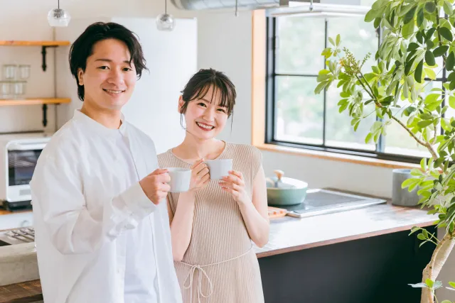 キッチンでカップを手にほほえむ二人
